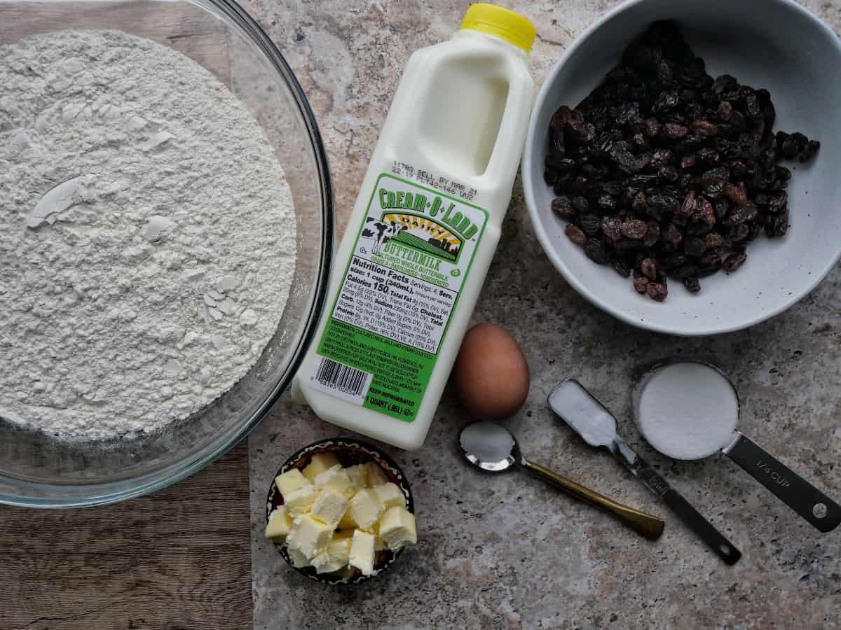 irish soda bread ingredients of buttermilk, flour, raisins, cold cubed butter, an egg, salt, baking soda, and sugar